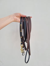 Load image into Gallery viewer, Black and brown leads in biothane, with gold and silver details.