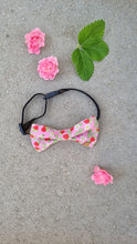 Load image into Gallery viewer, A dog bow tie with pink base, red strawberries, white flowers and green leaves.
