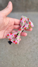 Load image into Gallery viewer, A dog bow tie with a pink base, red strawberries, white flowers and green leaves.
