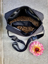 Load image into Gallery viewer, Black dog treat fanny pack with two compartments filled with different treats
